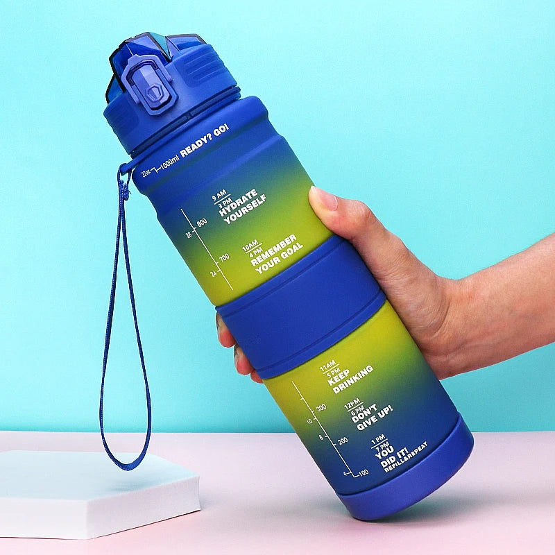 Eine Hand haelt eine blaue Wasserflasche mit Zeitmarkierungen und motivierenden Nachrichten gegen einen hellblauen Hintergrund.