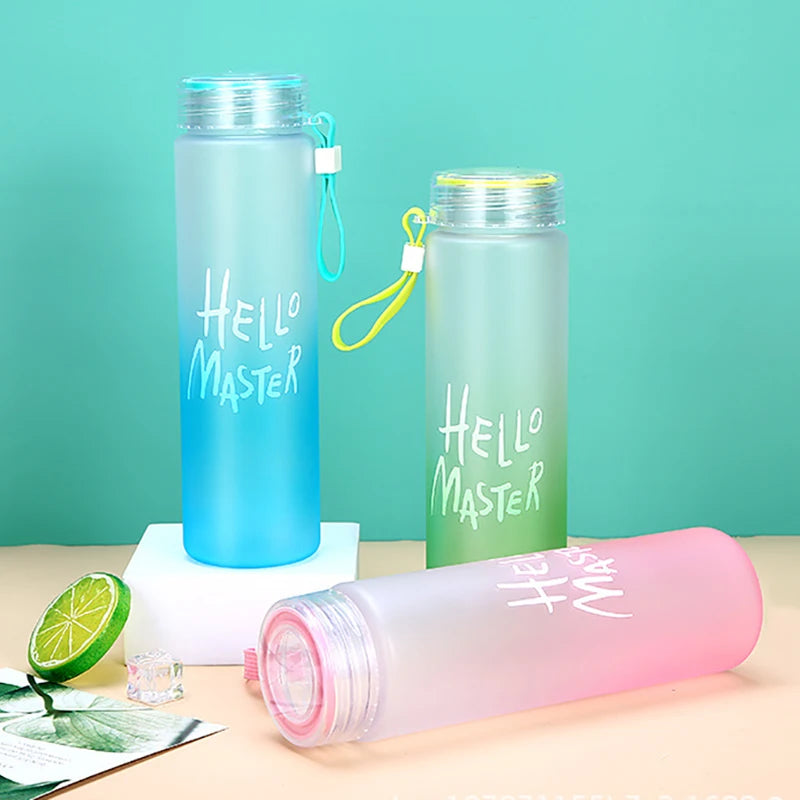 Drei Sport-Trinkflaschen mit Farben rosa die liegend ist, blaue auf einer weissen box und die gruene stehend und der Aufschrift "Hello Master", neben einer Limette und einem Eiswürfel. 