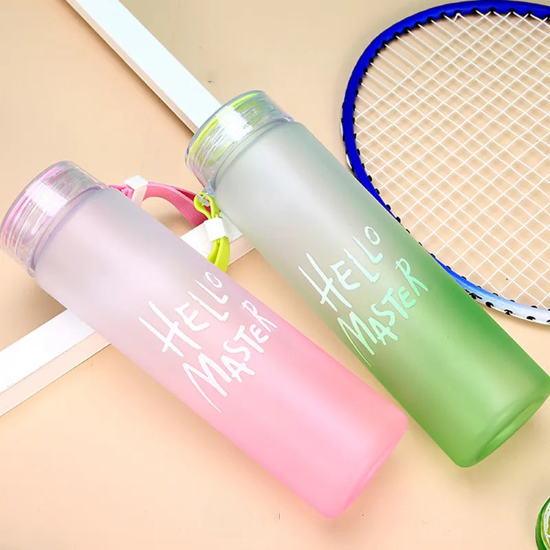 Zwei Sport-Trinkflaschen in pink und gruen mit der Aufschrift "Hello Master", neben einem Tennisschläger am Boden.