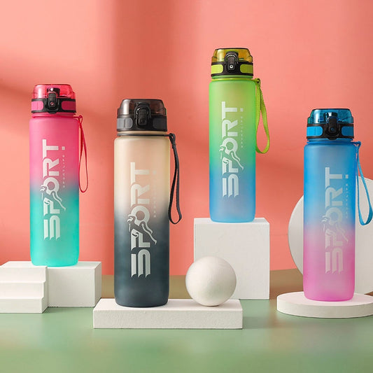 Vier farbige Sporttrinkflaschen mit dem Aufdruck 'SPORT' auf Podesten vor einem korallenfarbenen Hintergrund, jede Flasche mit einem individuellen Farbverlauf und einem befestigten Trageband.