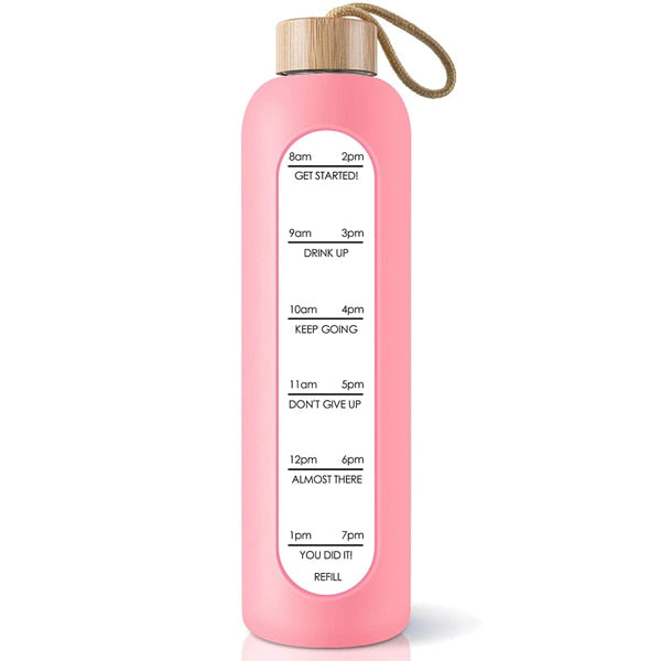 Eine pinke Glastrinkflasche mit Zeitmarkierungen und einem Bambusdeckel, versehen mit einem Jute-Trageband.