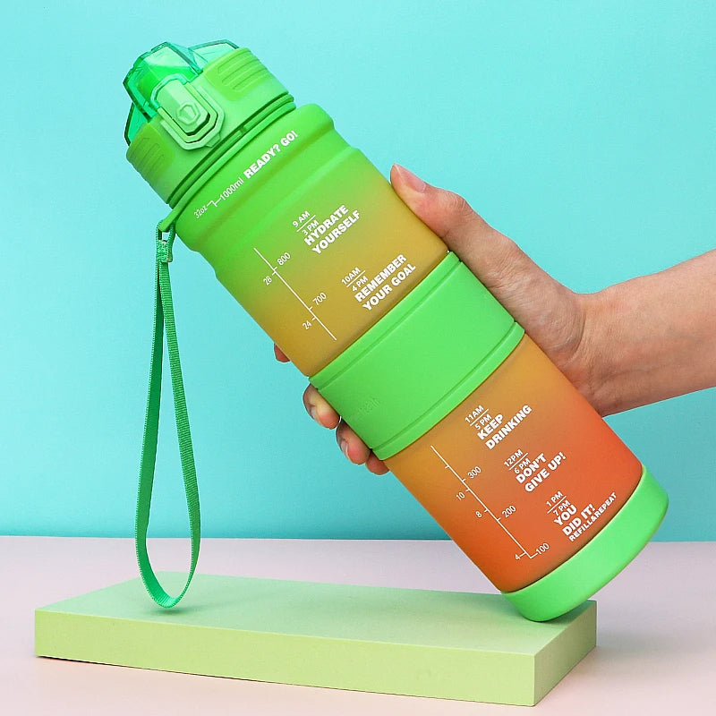 Eine Hand haelt eine gruen-orange Wasserflasche mit Zeitmarkierungen und motivierenden Nachrichten gegen einen hellblauen Hintergrund.