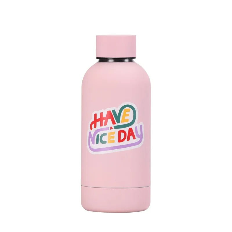Eine rosa Kinder-Thermosflasche aus Edelstahl mit dem farbenfrohen Aufdruck "HAVE A NICE DAY" in mehrfarbigen Buchstaben.