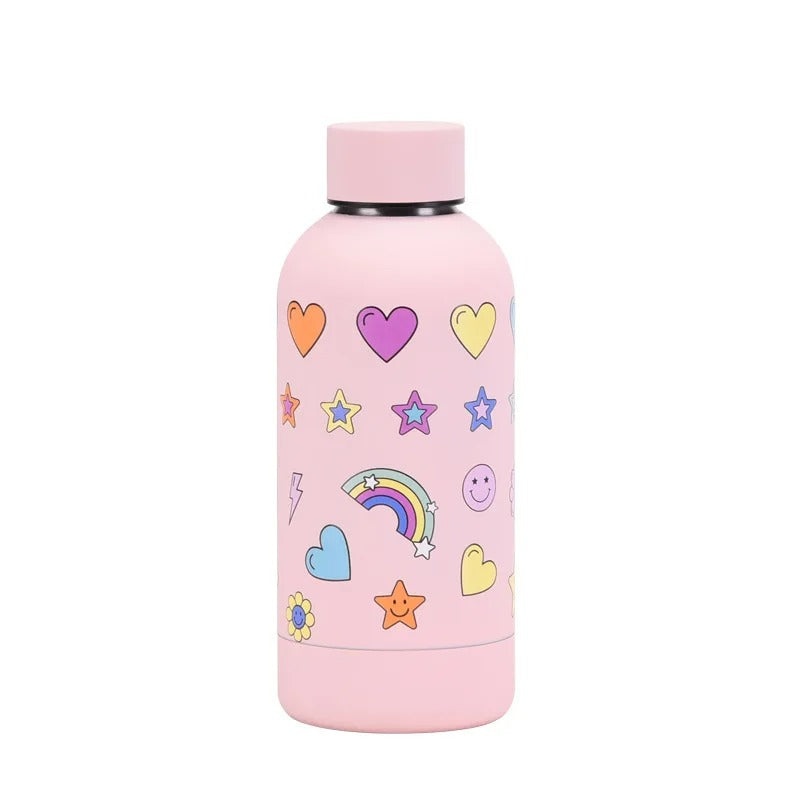 Eine rosa Kinder-Thermosflasche aus Edelstahl, verziert mit farbenfrohen Herzen, Sternen, einem Regenbogen, und anderen froehlichen Motiven.