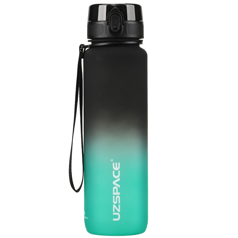 Eine Sporttrinkflasche mit einem Farbverlauf von schwarz zu gruen, ausgestattet mit einem Trageband und einem Klappdeckel. Auf der Flasche ist das Markenlogo "UZSPACE" sichtbar.