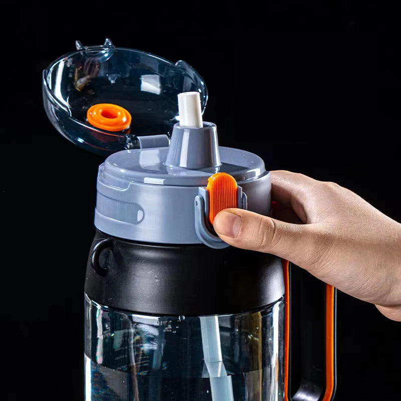 Eine Nahaufnahme einer Sport-Trinkflasche mit einem blauen Deckel und einem integrierten Strohhalm. Eine Hand bedient den orangefarbenen Verschlussmechanismus.
