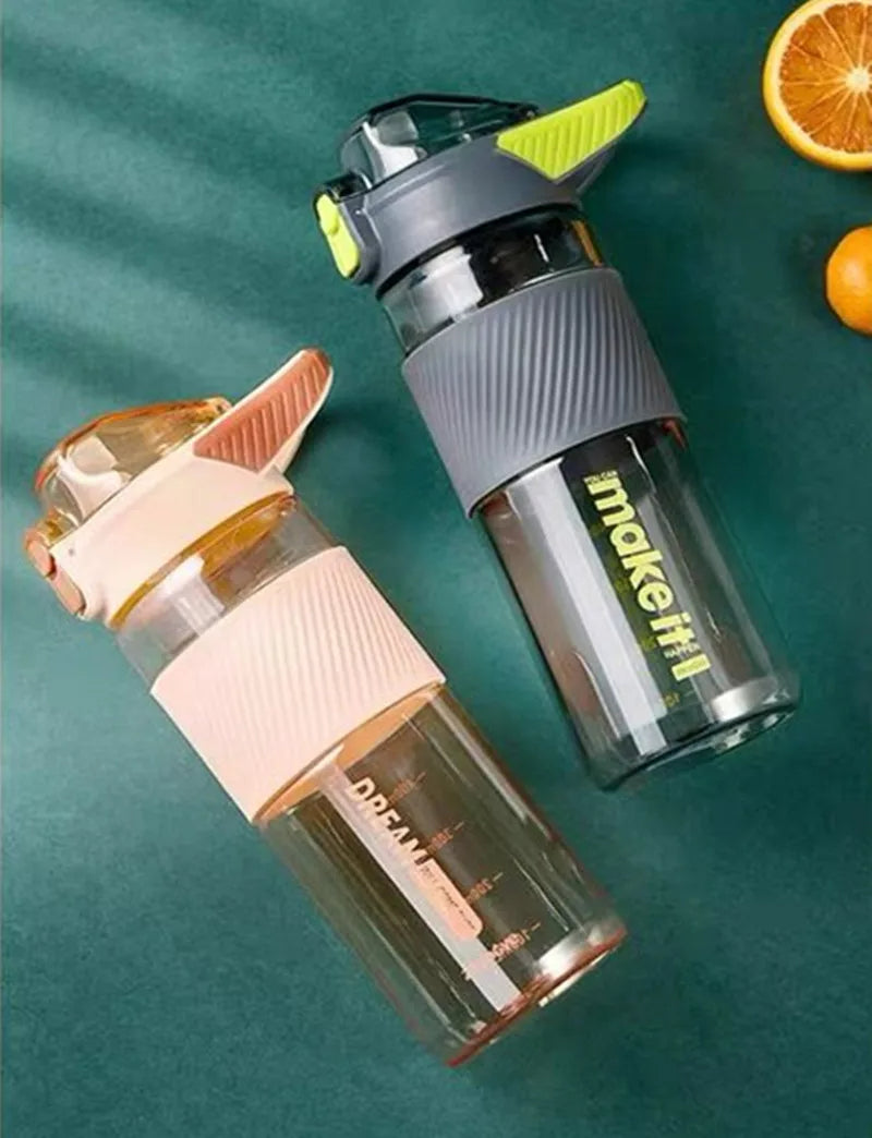 Zwei umgekippte Wasserflaschen auf einem gruenen Untergrund, umgeben von Zitrusfruechten.