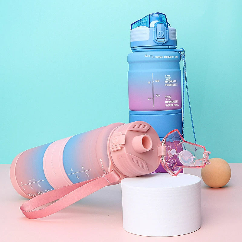 Zwei Wasserflaschen mit Zeitmarkierungen in Blau- und Rosa-Farbverlauf auf einem pastellfarbenen Hintergrund, neben einem Tennisball. Eine Flasche steht aufrecht, die andere liegt auf einem weißen Podest.