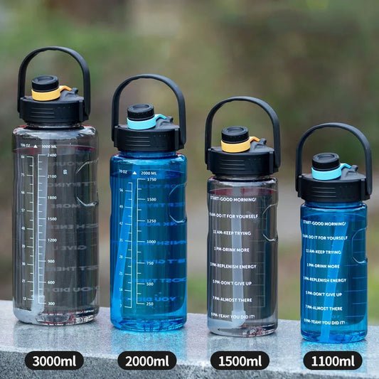 Vier wasserflaschen verschiedener Groessen und Farben mit Zeitmarkierungen und motivierenden Nachrichten darauf, aufgestellt auf einer grauen Oberflaeche im Freien.