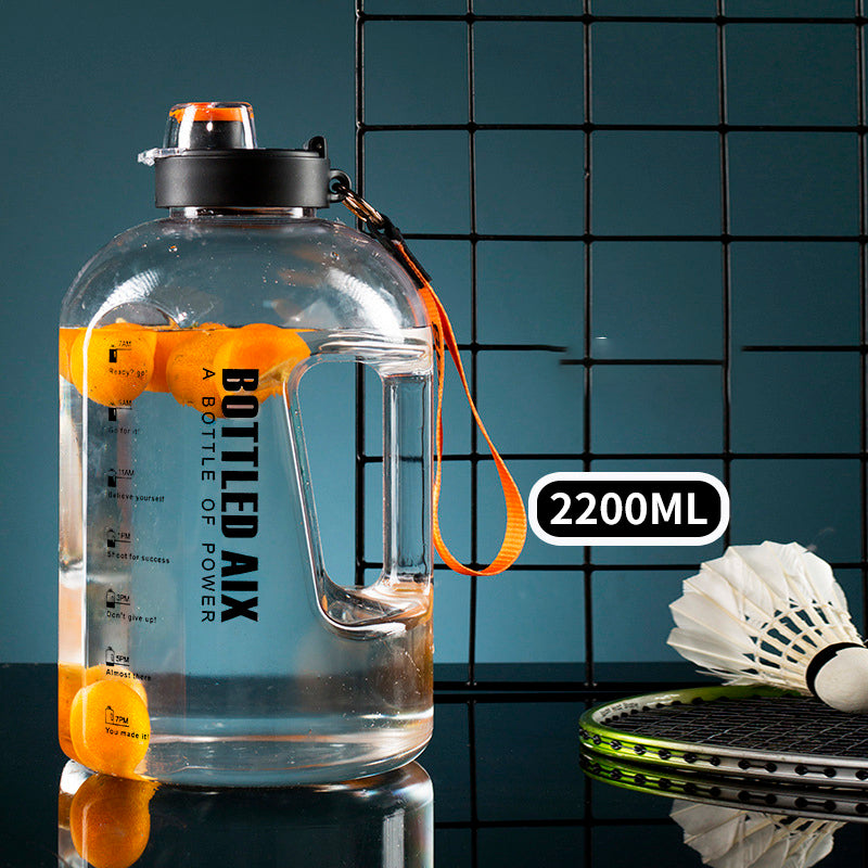 Transparente Sporttrinkflasche mit Orangenscheiben im Wasser, 2200ml Fuellmenge angezeigt, neben Badminton-Schlaeger und Federball auf dunklem Hintergrund