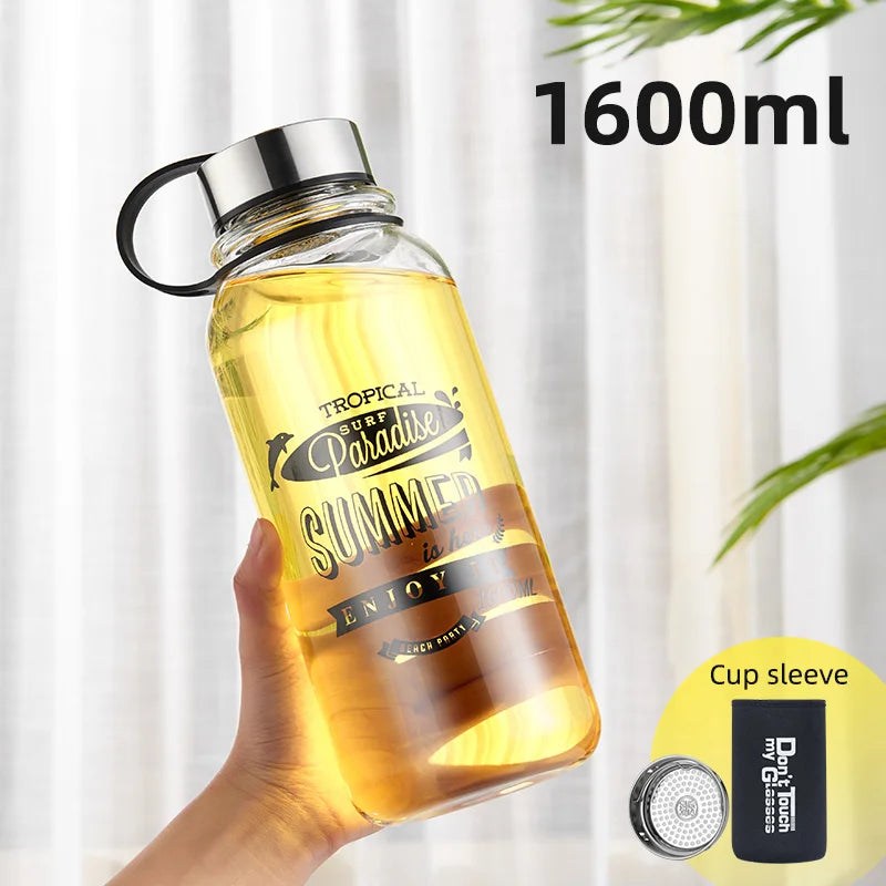 Eine handgehaltene gelbe Glaswasserflasche mit einem Fassungsvermoegen von 1600 ml. Auf der Flasche ist ein sommerliches Design mit den Worten "Tropical Surf Paradise SUMMER" und "ENJOY IT" gedruckt. Zusaetzlich ist ein "Cup sleeve" abgebildet.