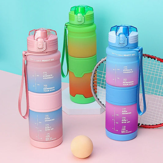 Drei farbige Wasserflaschen mit motivierenden Zeitmarkierungen fuer den ganzen Tag, begleitet von einem Tennisball und Schlaeger auf einem pastellfarbenen Hintergrund.