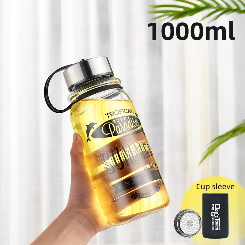 Eine handgehaltene gelbe Glaswasserflasche mit einem Fassungsvermoegen von 1000 ml. Auf der Flasche ist ein sommerliches Design mit den Worten "Tropical Surf Paradise SUMMER" und "ENJOY IT" gedruckt. Zusaetzlich ist ein "Cup sleeve" abgebildet.