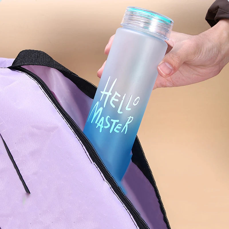 Eine blaue Sport-Trinkflasche mit der Aufschrift "Hello Master", die mit der Hand aus einer lila Sporttasche gehalten wird.