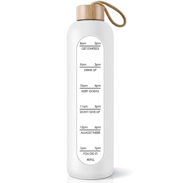 Eine weisse Glastrinkflasche mit Zeitmarkierungen und einem Bambusdeckel, versehen mit einem Jute-Trageband.