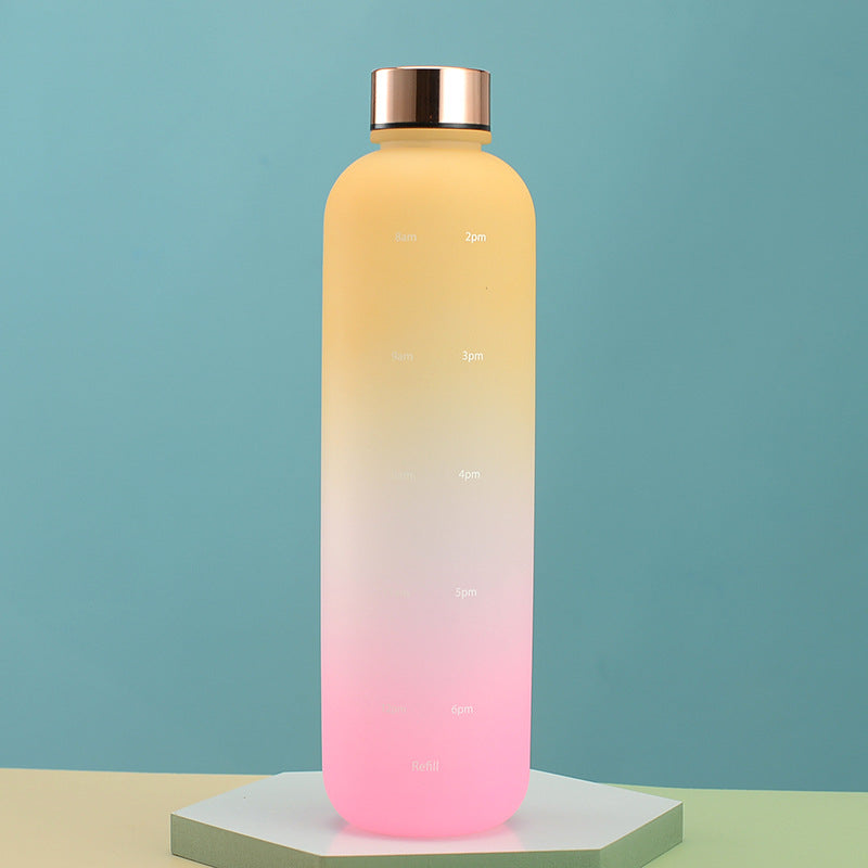 Eine Trinkflasche mit einem Farbverlauf von Gelb zu Pink und Zeitmarkierungen steht auf einem Podest vor einem Blauem Hintergrund.
